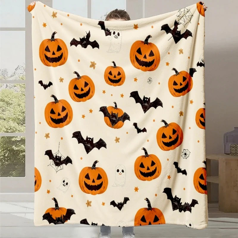 Couverture moelleuse à motif de citrouilles d'Halloween et de chauve-souris sur fond beige, créant une atmosphère festive et effrayante pour la saison.