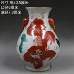 Vase décoratif traditionnel en céramique peint de motifs floraux et animaliers rouges et verts sur fond craquelé blanc.
