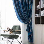 Chat sur un fauteuil vert à côté d’un rideau bleu foncé à motifs modernes dans un intérieur design