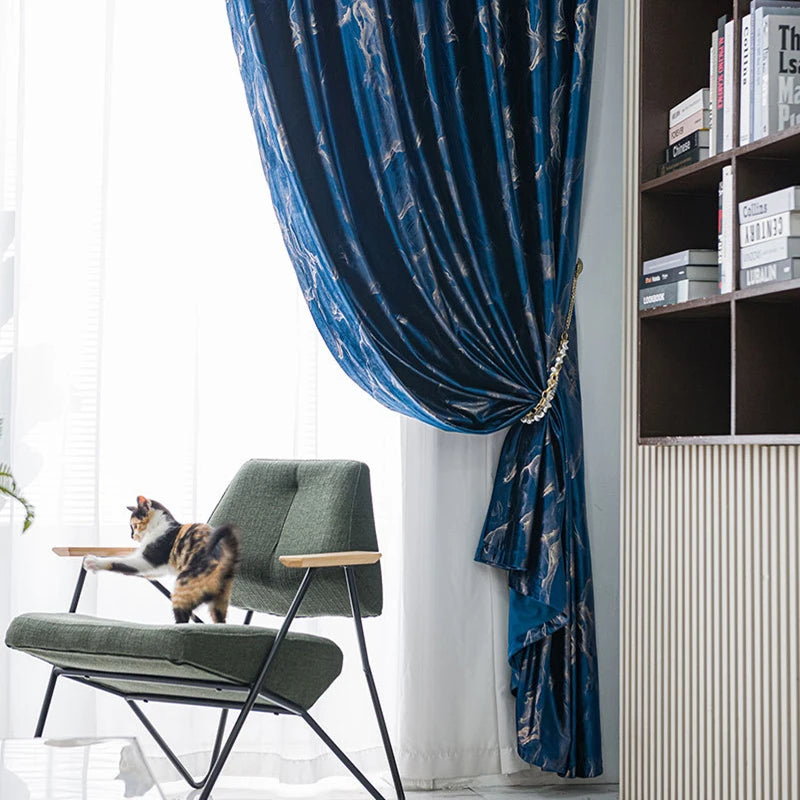 Chat sur un fauteuil vert à côté d’un rideau bleu foncé à motifs modernes dans un intérieur design