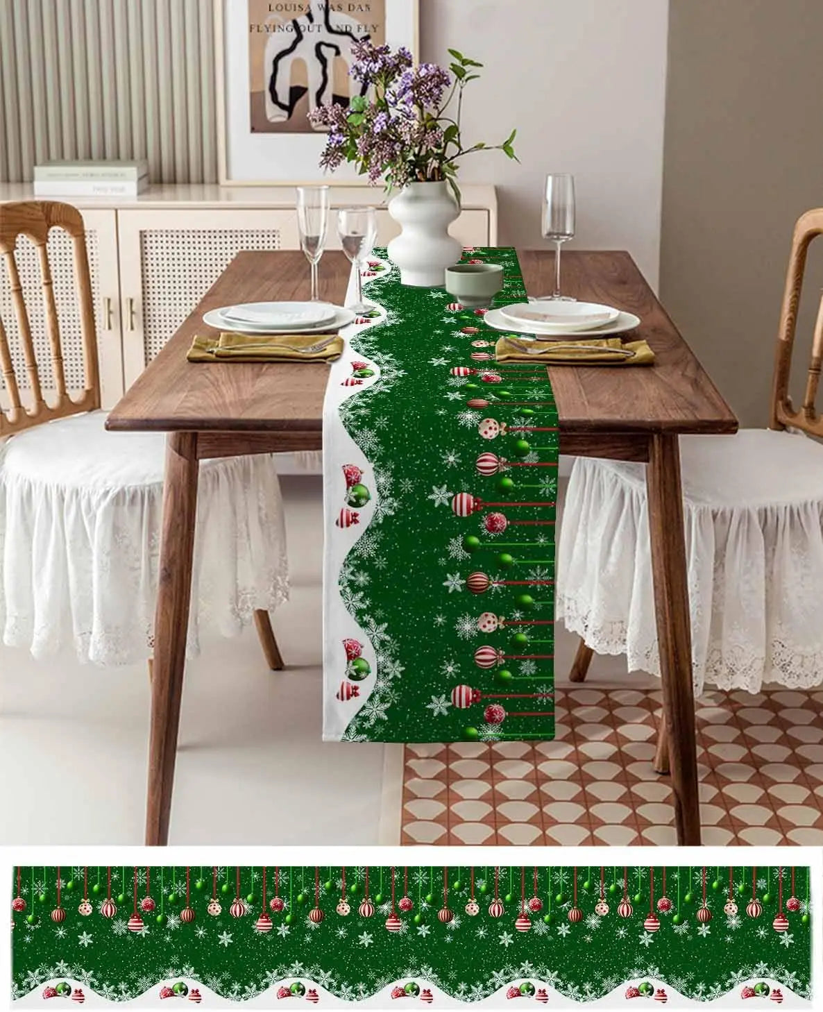 Table décorée pour Noël avec un chemin de table vert imprimé de boules de Noël rouges, de flocons de neige et d'éléments décoratifs, accompagné d'un bouquet de fleurs dans un vase blanc.