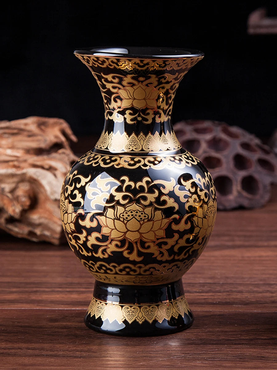 Vase décoratif en céramique noire et dorée avec motifs floraux ornementaux, posé sur une surface en bois sombre.