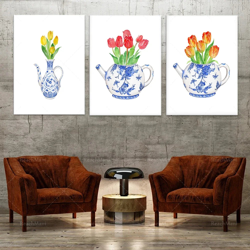 Trois tableaux décoratifs montrant des bouquets de tulipes dans des vases en céramique bleue et blanche, disposés sur un mur en béton brut, avec deux fauteuils en velours marron et une table basse en bois à leur pied.
