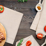 Une table en bois rustique avec des ustensiles de cuisine, des légumes frais et des serviettes en tissu, créant une atmosphère culinaire accueillante.