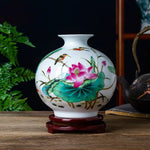 Magnifique vase en porcelaine peint à la main avec des motifs de lotus fleurissants et des colibris voltigeant parmi les feuilles vertes.