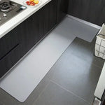 Cuisine moderne avec comptoir en acier inoxydable et carrelage gris, offrant un espace de travail pratique et un style épuré.
