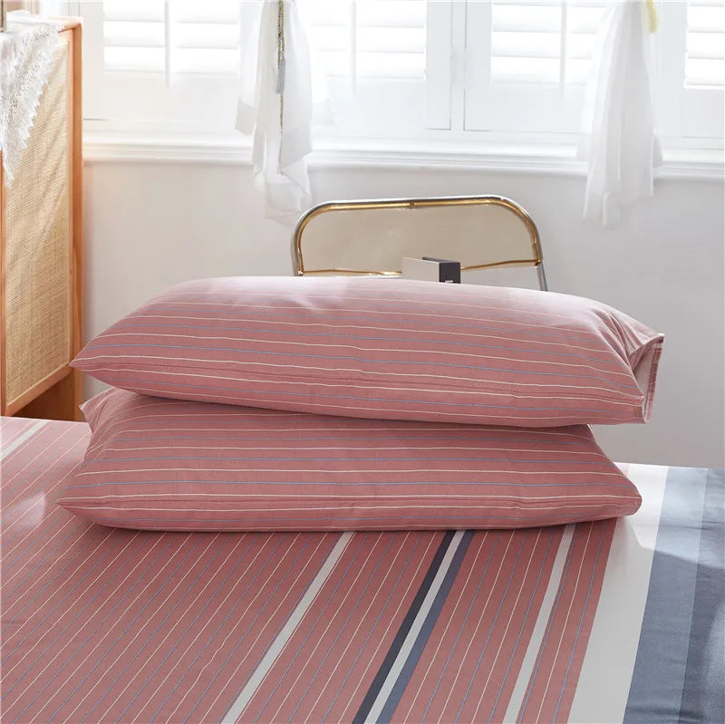 Des oreillers roses rayés, disposés sur un lit, dans une chambre aux tons clairs et apaisants.