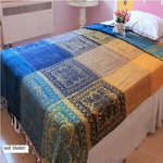 Couverture murale rectangulaire colorée avec des motifs floraux et geometriques en bleu, jaune et beige.