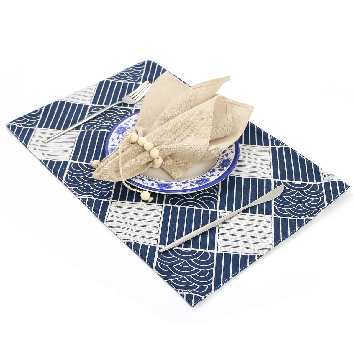 Magnifique service de table avec un motif japonais élégant et une serviette beige nouée sur une assiette en céramique bleue.