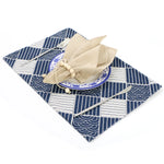 Magnifique service de table avec un motif japonais élégant et une serviette beige nouée sur une assiette en céramique bleue.