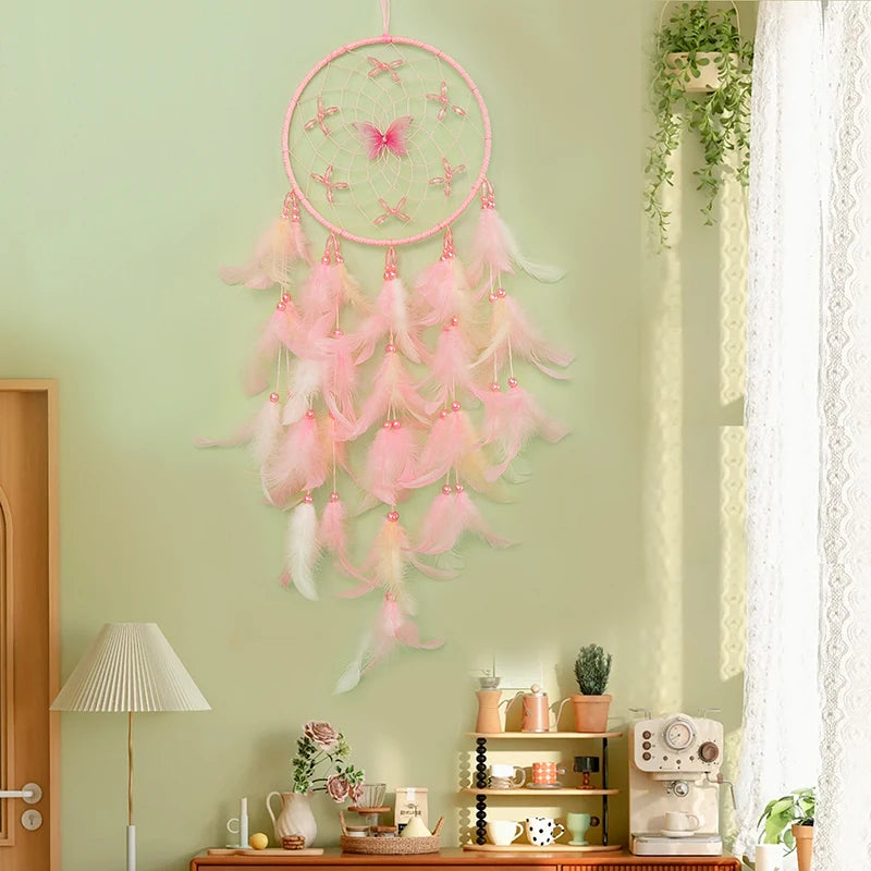 Un capteur de rêves rose suspendu devant une fenêtre, avec des plumes douces et légères, créant une atmosphère paisible et féminine dans cette pièce décorée avec soin.