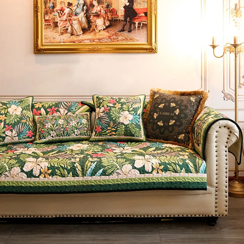 Un canapé décoré de coussins aux motifs floraux luxuriants, posé devant une oeuvre d'art encadrée dans un intérieur chic et élégant.