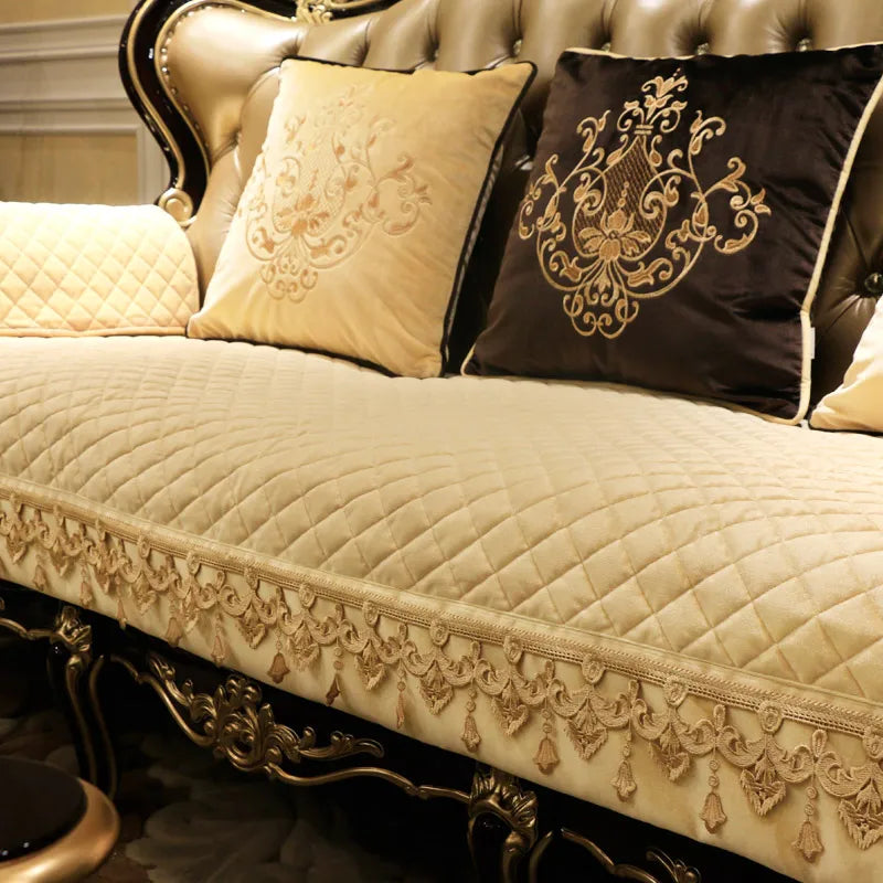 Un canapé élégant orné de décorations dorées, de coussins brodés et d'une couverture matelassée créant une atmosphère luxueuse.