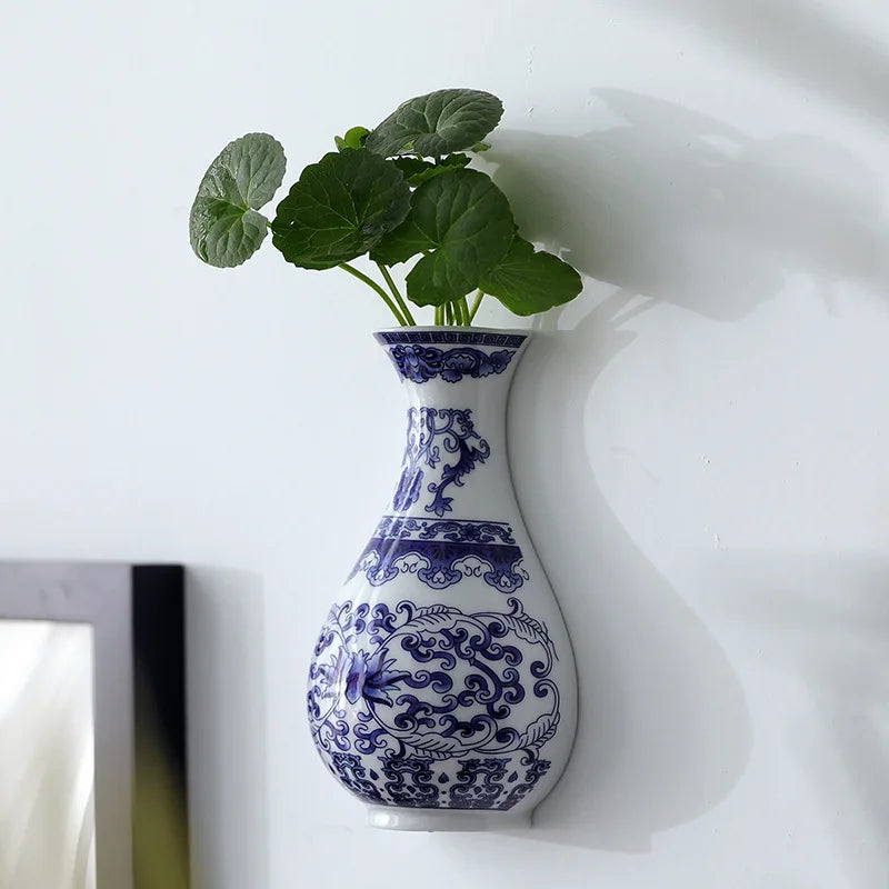 Un vase en céramique bleue et blanche décoré de motifs floraux ornementaux, rempli de feuilles vertes fraîches.