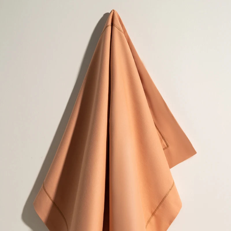 Cette serviette de bain rose pâle est soigneusement pliée pour créer une forme triangulaire élégante, projetant une atmosphère apaisante et relaxante.