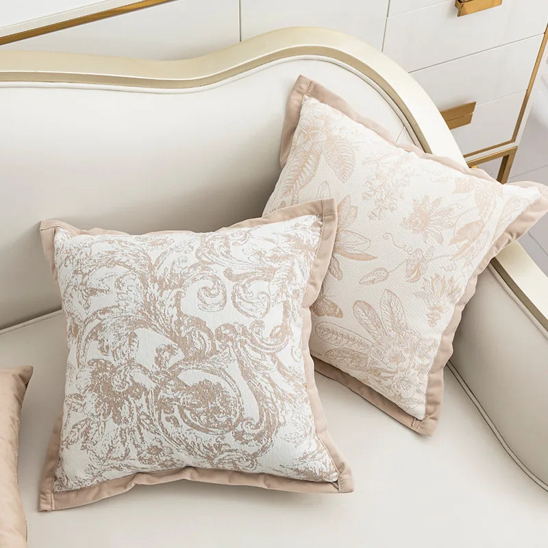 Deux oreillers décoratifs élégants avec un motif floral beige et blanc sur un lit lumineux.