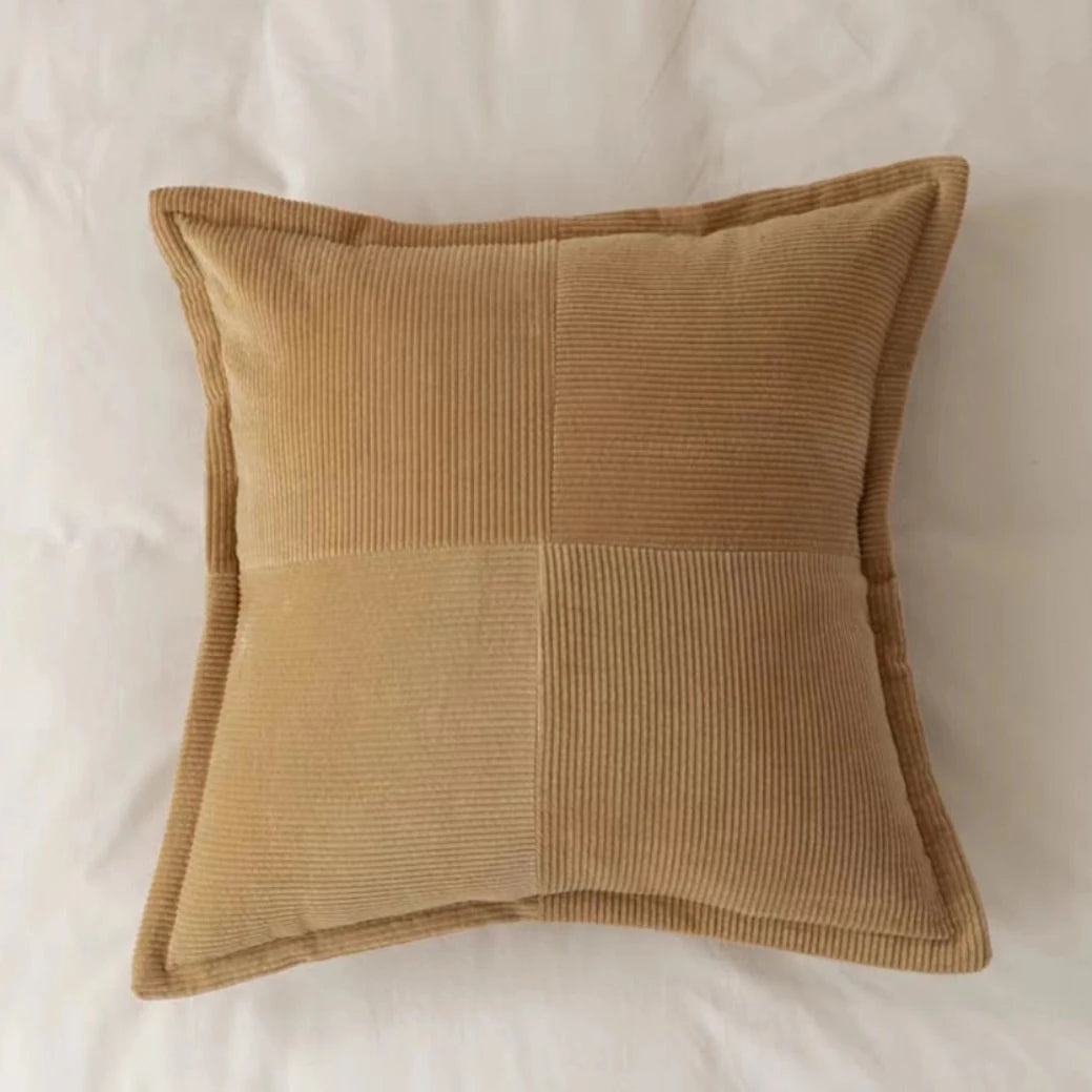 Coussin décoratif carré en velours côtelé beige aux teintes neutres.