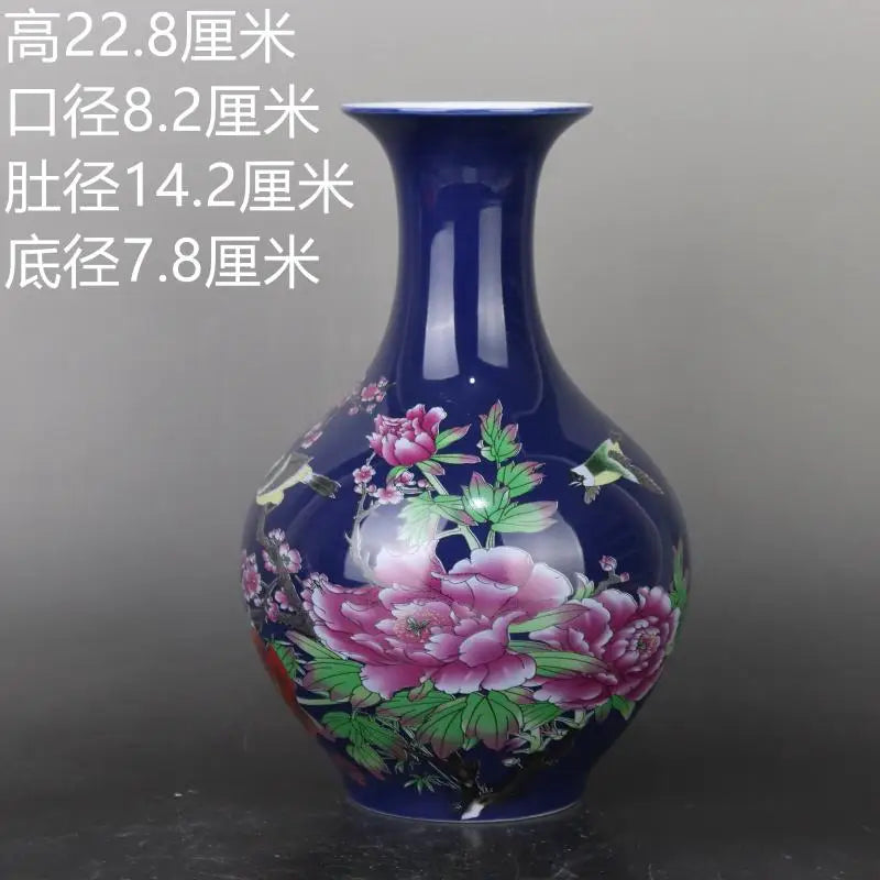 Vase en céramique bleu foncé orné de fleurs de pivoines roses épanouies sur une surface sombre.