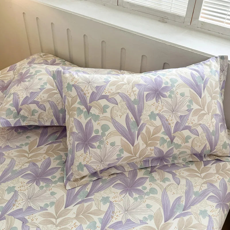 Cette image montre un ensemble de literie composé d'un motif floral délicat aux tons violet et beige, avec des feuilles et des fleurs stylisées qui créent une atmosphère paisible et apaisante dans la chambre.