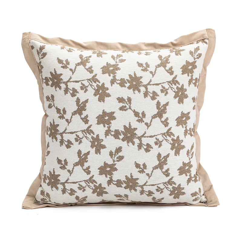 Coussin décoratif beige avec un motif floral brun élégant.