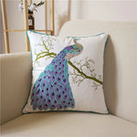 Un coussin décoratif avec un paon élégant aux couleurs vives, perché sur une branche d'arbre, créant une scène de nature apaisante.
