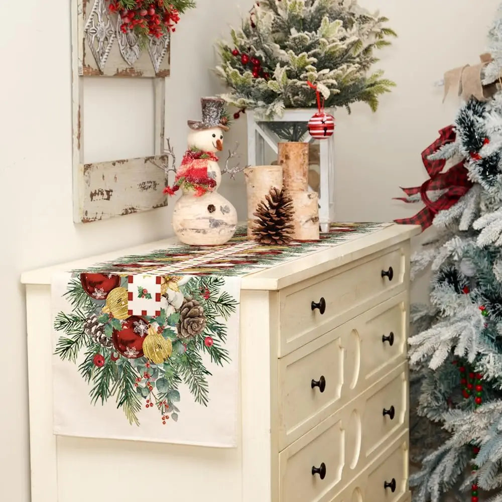 Un meuble vintage décoré avec des ornements et des éléments de Noël, notamment un petit bonhomme de neige, des cônes de pin et des branches enneigées, créant une ambiance festive et chaleureuse.