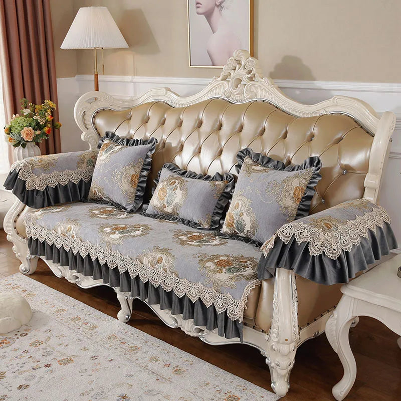 Un canapé victorien en cuir capitonné, décoré de coussins ornés de dentelle et de motifs floraux.