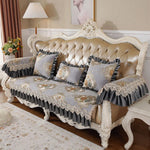 Un canapé victorien en cuir capitonné, décoré de coussins ornés de dentelle et de motifs floraux.