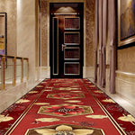 Couloir élégant d'un hôtel avec un tapis richement décoré de motifs floraux rouges et dorés.