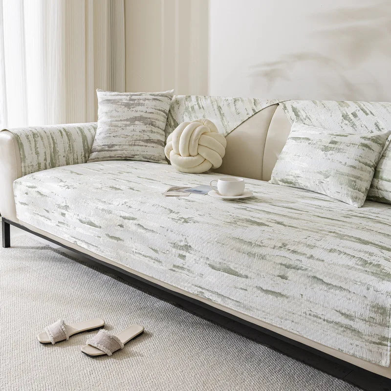 Un sofa confortable tapissé de motifs gris et blancs, avec des coussins de décoration, une table et une tasse posées sur le côté, créant une atmosphère chaleureuse et harmonieuse dans cet espace de détente.