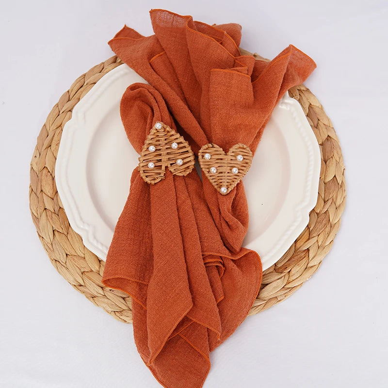 Un beau set de table en vannerie doré rehaussé de serviettes en tissu orange ornées de motifs élégants en perles.