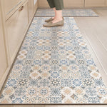 Tapis de couleur beige, bleu et gris, avec un motif géométrique élégant, posé sur un sol carrelé dans une cuisine.