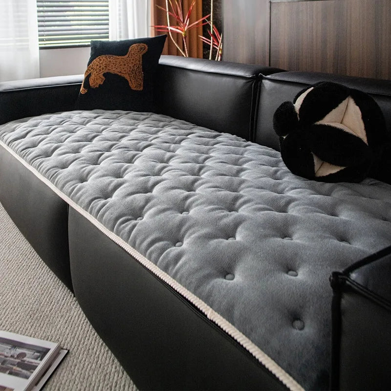Un canapé gris confortable avec des coussins noirs et une décoration de chambre chaleureuse.