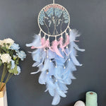 Un magnifique capteur de rêves circulaire orné de plumes bleues et roses, suspendu sur un fond noir, entouré de bouquets de fleurs.
