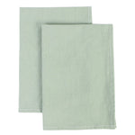 Des serviettes en tissu vert pâle, avec des ourlets simples, offrant une touche de fraîcheur et de simplicité.