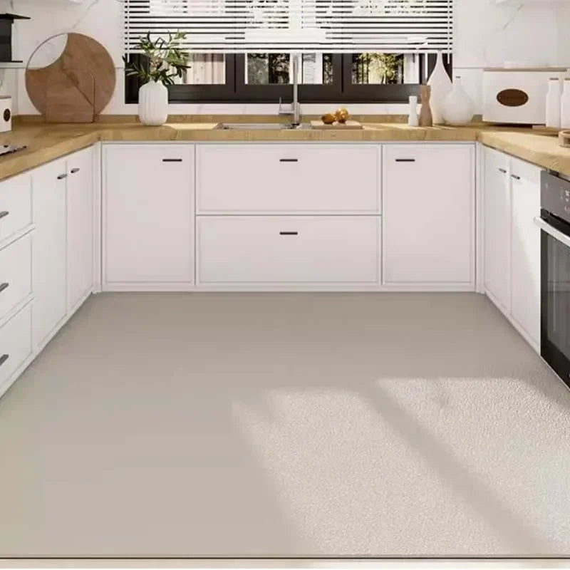 Une cuisine moderne et épurée avec des meubles blancs, des plans de travail en bois et de grands espaces vitrés offrant une vue dégagée sur l'extérieur.