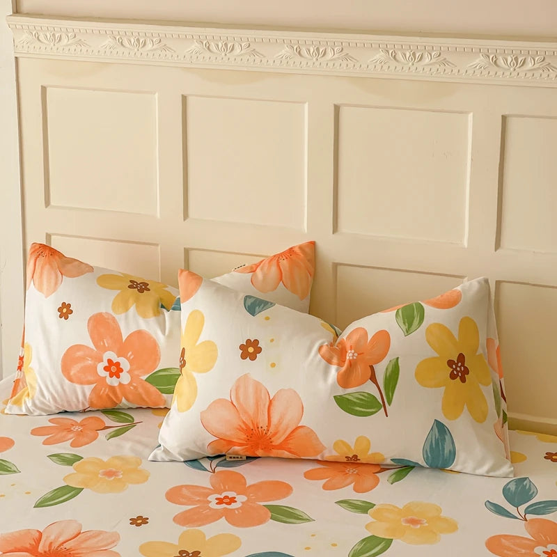 Des oreillers colorés aux motifs de fleurs jaunes et orange, posés sur un lit blanc contre un mur décoré de moulures.