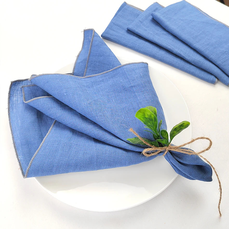 Serviettes de table bleues décorées d'une fleur verte, disposées sur une assiette blanche.