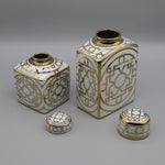 Ensemble de boîtes décoratives en porcelaine blanche et dorée avec des motifs géométriques élégants.
