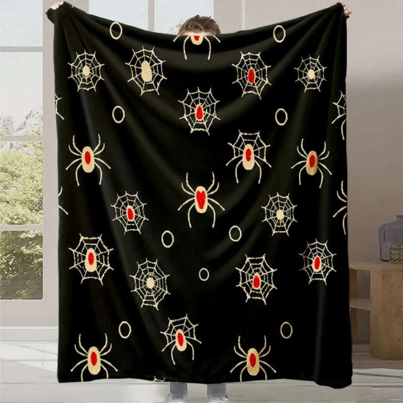 Une couverture noire décorée de motifs d'araignées et de toiles d'araignée dorés, idéale pour une ambiance Halloween.