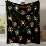 Une couverture noire décorée de motifs d'araignées et de toiles d'araignée dorés, idéale pour une ambiance Halloween.