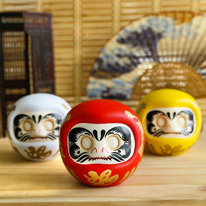 statuette japonaise daruma rouge blanche visage sourire yeux grands ouverts motifs dorés traditionnels décoration
