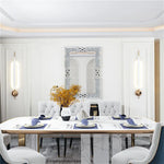 Intérieur élégant de salle à manger avec table de style moderne, miroir décoratif et luminaires appliques.