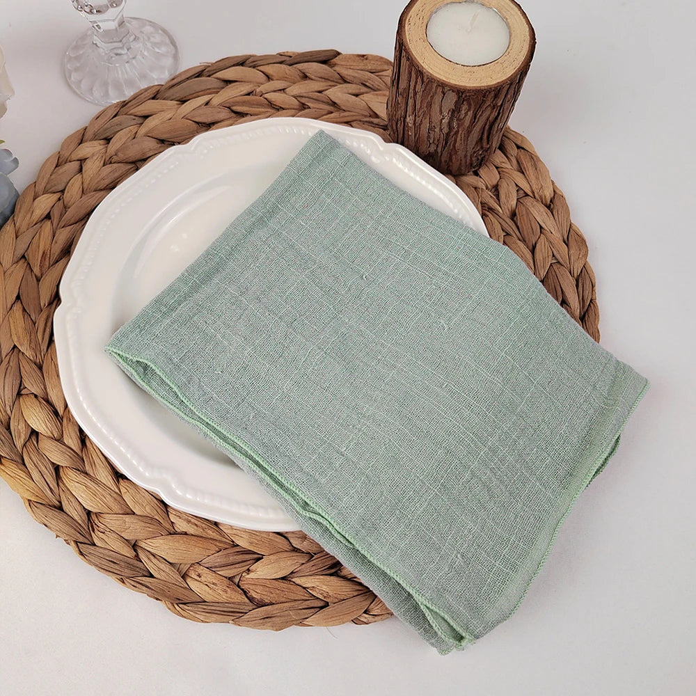 Sur une serviette en osier tressé, une assiette blanche est posée avec un linge de cuisine en lin vert menthe.