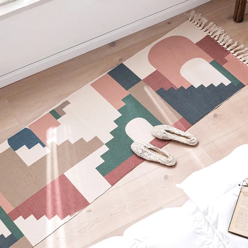 Un tapis coloré abstrait avec des formes géométriques et des couleurs pastel créant une scène montagnarde apaisante.