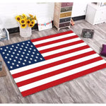 Ce tapis représente le drapeau américain avec ses rayures rouges et blanches ainsi que ses étoiles bleues sur un fond blanc. Il est posé sur un sol en bois et est entouré de décorations florales et de cadres dans un intérieur avec une atmosphère chaleureuse et accueillante.