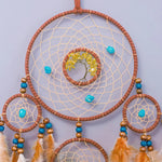 Captivante composition de capteurs de rêves avec un arbre de vie en pierre jaune et des accents turquoise, suspendus au milieu d'un motif de toile d'araignée en fibre naturelle.
