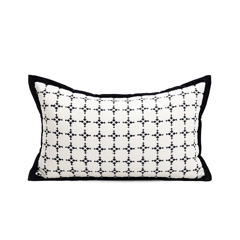 Coussin décoratif rectangulaire avec un motif géométrique en noir et blanc, avec une bordure noire sur les bords.