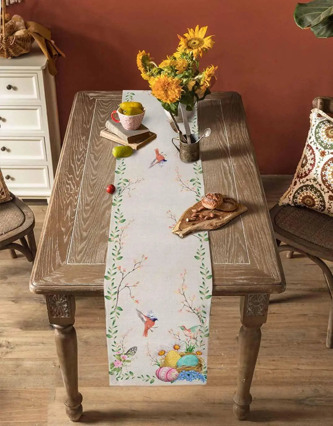Une table rustique en bois décoré avec un chemin de table coloré, un bouquet de fleurs jaunes et des éléments décoratifs.
