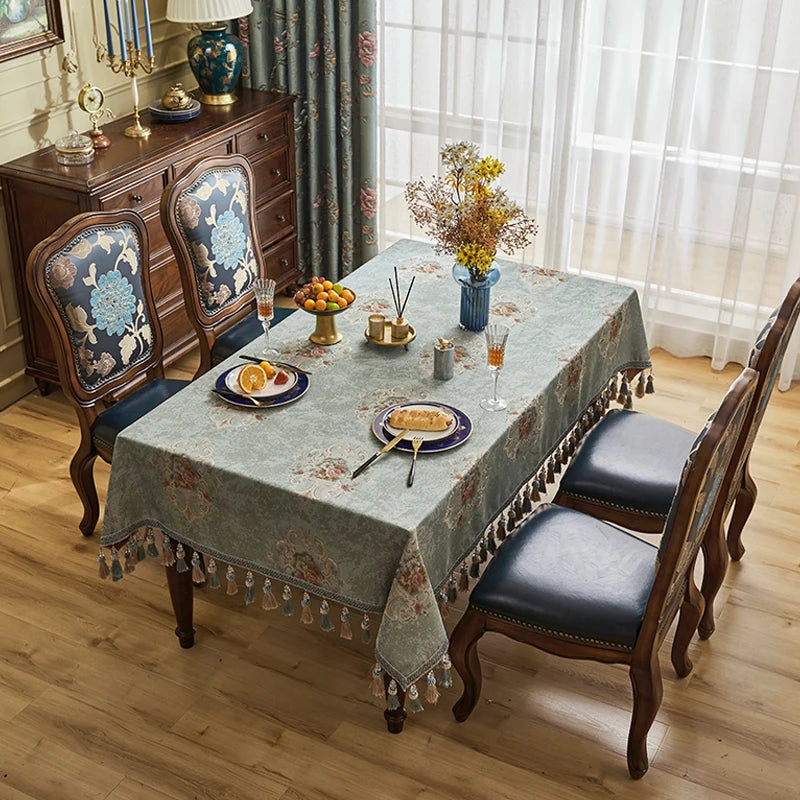 Une salle à manger élégante avec une table en bois sombre, des chaises rembourrées noires et un buffet décoré de motifs floraux, accompagnés de décors et accessoires de style vintage.